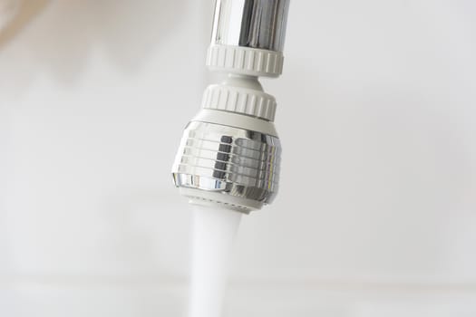 a kitchen faucet with water flowing with a white background