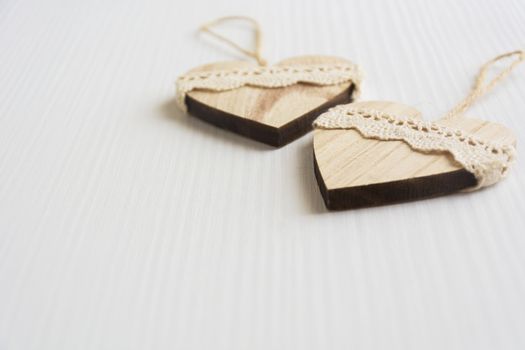 two wooden heart placed nicely on a white wood background