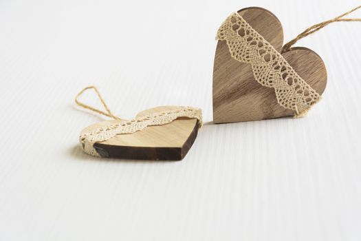 two wooden heart placed nicely on a white wood background