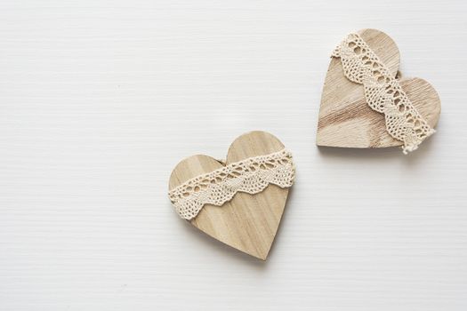 two wooden heart placed nicely on a white wood background