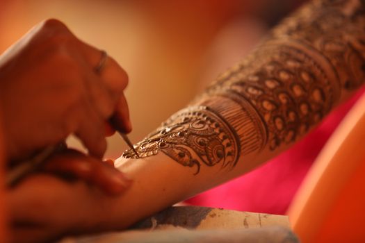 An artist making a beautiful henna or mehendi design on the hand of an Indian wife.