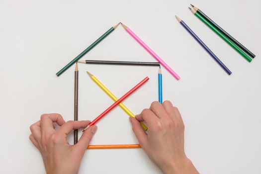Women's hands are building a house from pencils