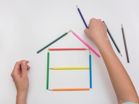 Women's hands are building a wooden house from pencils