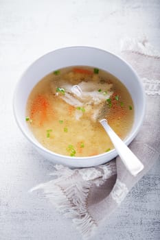 Homemade chicken soup with a spoon on a wooden surface