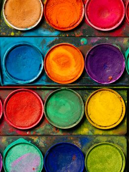 Photo of a palette of watercolor paints and well-used tray.