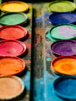 Photo of a palette of watercolor paints on a well-used tray.