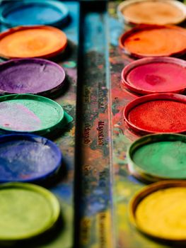 Photo of a palette of watercolor paints on a well-used tray.