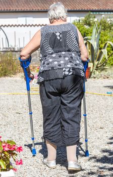 Portrait of Senior woman walking with crutches in her garden