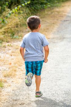 portrait of little boy running along a country road