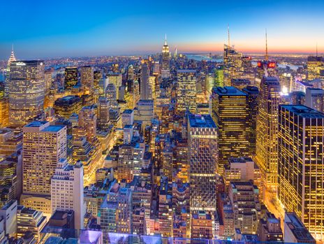 New York City. Manhattan downtown skyline with illuminated Empire State Building and skyscrapers at dusk seen from Top of the Rock observation deck.