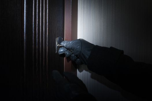man wearing gloves opens the door at night.
