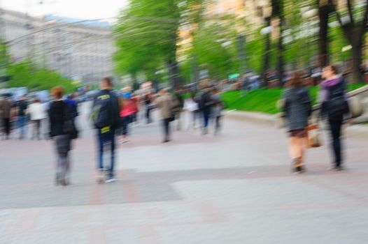 Blurred image of people walking at day in park with bokeh for background usage.