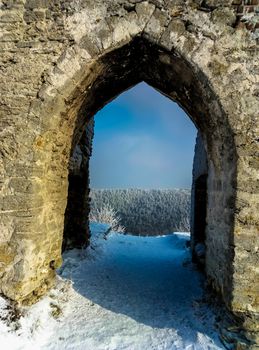 beautiful view of the forest through an archway of the ruins of the old castle