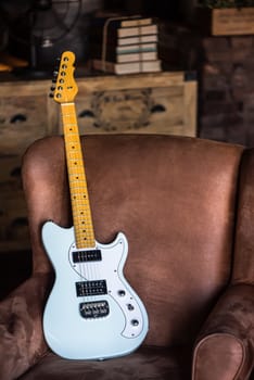 Electric Guitar Leaning Against a Couch with Grunge Background. Electric Guitar Light Blue Finish. Still life with Electric Guitar.