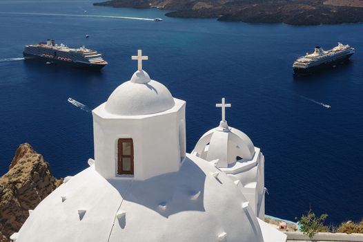 White orthodox church bell tower and sea with ships at background. Fira, Santorini Greece. Copyspace