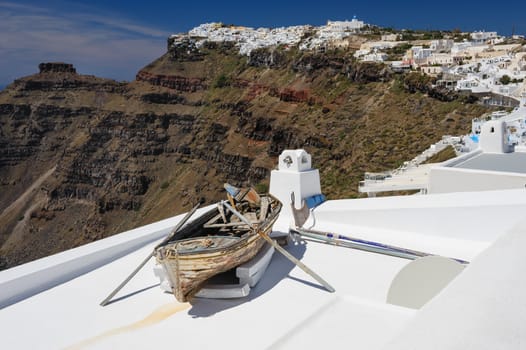 Old wooden fishermans''s boat on roofof house in Firostefani village with typical white architecture, Santorini island, Greece