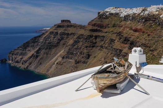 Old wooden fishermans''s boat on roofof house in Firostefani village with typical white architecture, Santorini island, Greece