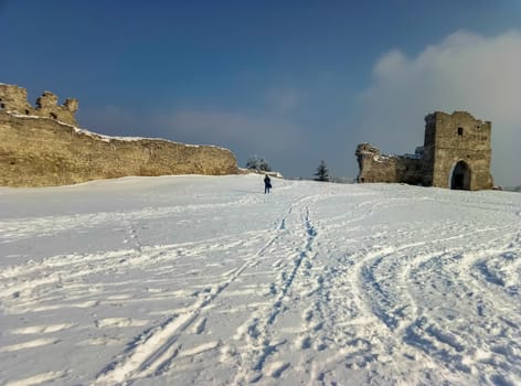 the ruins of the old castle on the background of white snow and blue sky