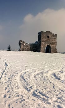 the ruins of the old castle on the background of white snow and blue sky