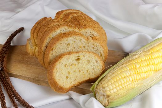 bread made from corn on the white fabric. Slices of corn bread laying on a chopping Board and Sweet corn cobs