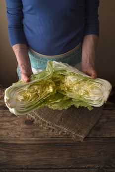Woman shares the Chinese cabbage into two halves on the napkin vertical