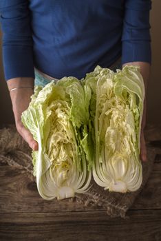 Woman holding two halves of the Chinese cabbage on the table vertical