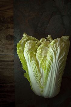 Chinese cabbage on a gray slate on old boards vertical