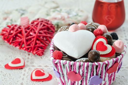 Basket with chocolates, cookies and a decorative Valentines day hearts. Selective focus.