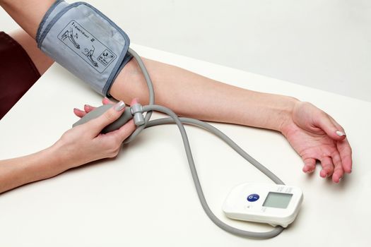 Woman measures her blood pressure, isolated on white background