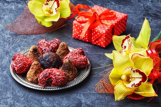 Chocolate truffles with cocoa and nuts and red box with gift