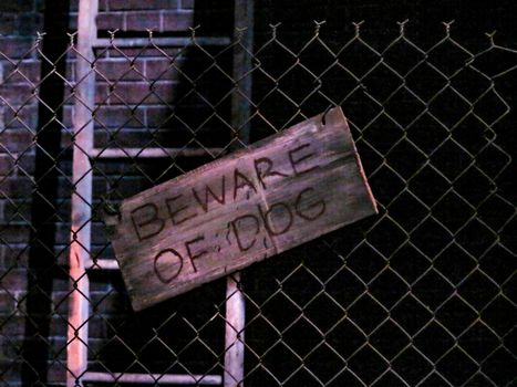 A Beware of the Dog sign on a wire fence