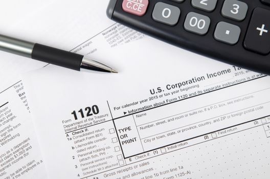 US tax form 1120 with pen and calculator. tax form law document usa white mathematics business concept