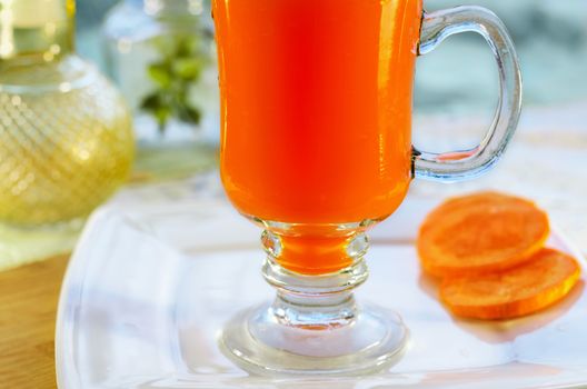 Carrot juice in glass on the stem and a piece of carrot, close-up can not see the edge. Selective focus.