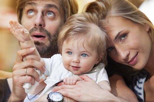 A little cute baby boy with his young parents are having fun outdoors.