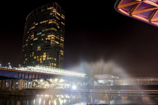 Tall iluminated skyscraper in a wharf at night