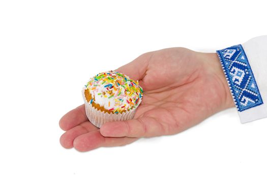 Little Easter cake decorated with white icing and colorful sugar decors in male hand on a light background
