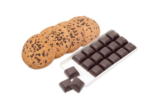 Several chocolate chip cookie and square pieces of dark chocolate in the opened packing on a light background
