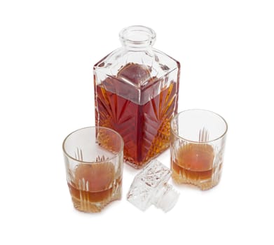 Opened decanter and two glasses with whiskey, stopper from the decanter on a light background
