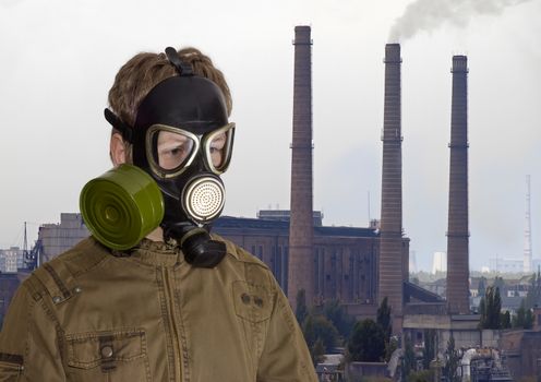 Man in a rubber gas mask against the backdrop of a thermal power station with several brick flue-gas stacks
