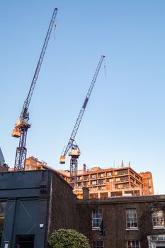 Two cranes in a construction site just behind one of the biggest hospitals in London