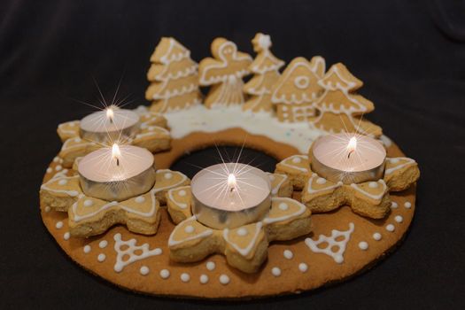 gingerbread wreath and lit candles on a dark background