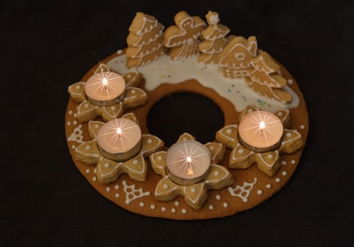 gingerbread wreath and lit candles on a dark background