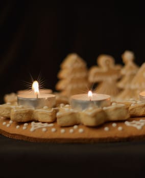 gingerbread wreath and lit candles on a dark background vertical view