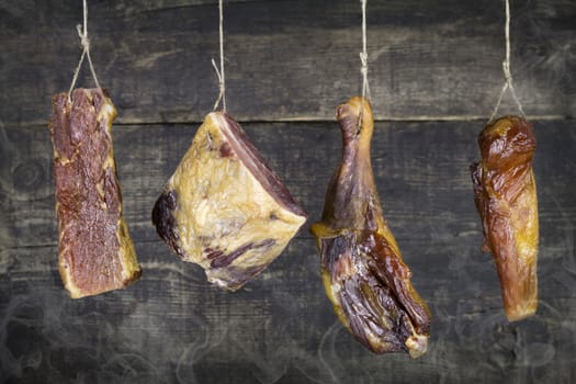 Smoked Meat Hanging on the Rope Against Wooden Background With Smoke