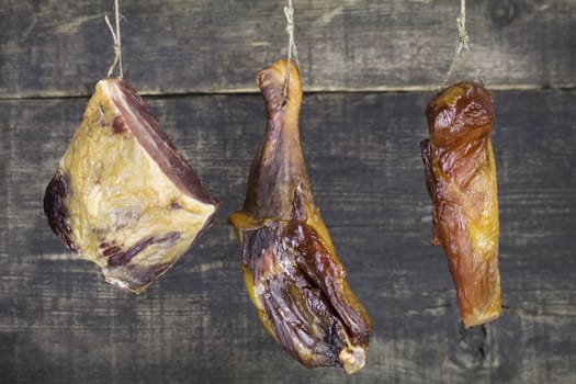 Smoked Pork and Chicken Meat Hanging on the Rope Against Wooden Background