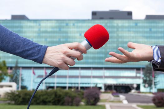 Reporter interviewing businessman, corporate building in background