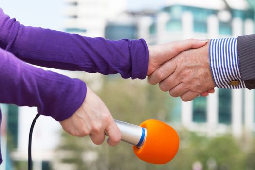 Businessperson and a female journalist shaking hands before media interview