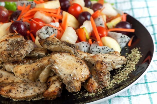 Healthy food. Grilled chicken sprinkled with oregano and mix fruit salad spicy on a plate.