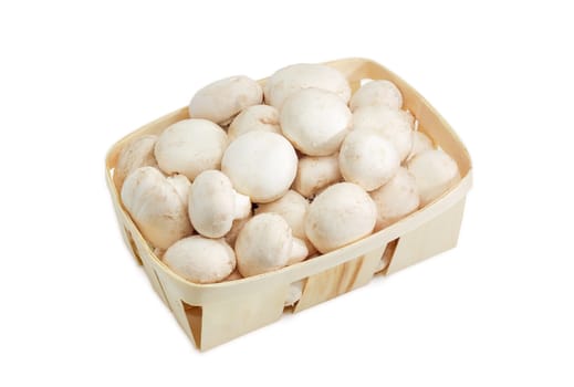 Fresh cultivated common button mushrooms in the wooden basket on a light background 
