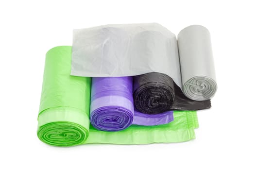 Several rolls of plastic disposable garbage bags of different sizes and colors including biodegradable on a light background
